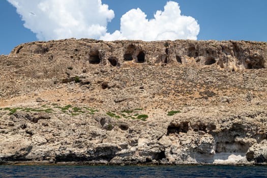 View from a motor boat on the mediterranean sea at the rocky coastline near Stegna on the eastside of Greek island Rhodes on a sunny day in spring