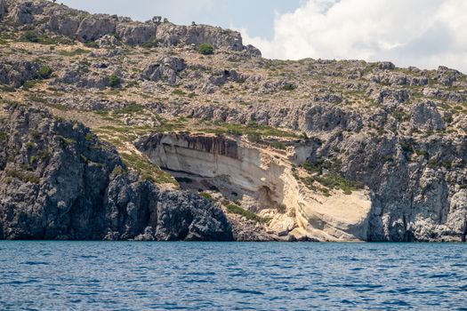 View from a motor boat on the mediterranean sea at the rocky coastline near Stegna on the eastside of Greek island Rhodes on a sunny day in spring