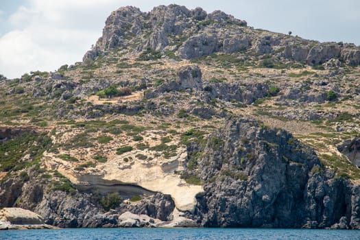 View from a motor boat on the mediterranean sea at the rocky coastline near Stegna on the eastside of Greek island Rhodes on a sunny day in spring