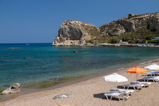 Stegna beach on Greek island Rhodes with sand, sunshades and boats in the background on a sunny day in spring