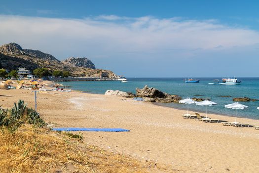 Stegna beach on Greek island Rhodes with sand, sunshades and boats in the background on a sunny day in spring