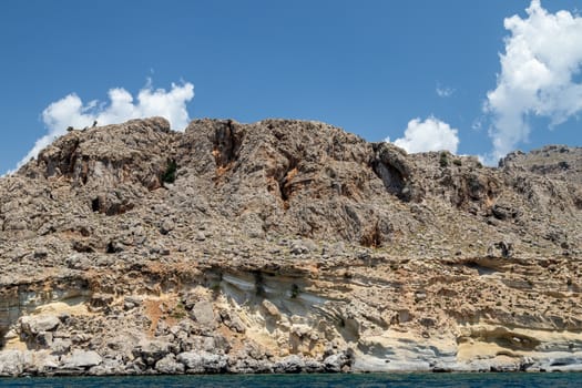 View from a motor boat on the mediterranean sea at the rocky coastline near Stegna on the eastside of Greek island Rhodes on a sunny day in spring
