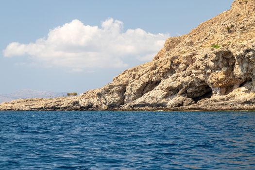 View from a motor boat on the mediterranean sea at the rocky coastline near Stegna on the eastside of Greek island Rhodes on a sunny day in spring