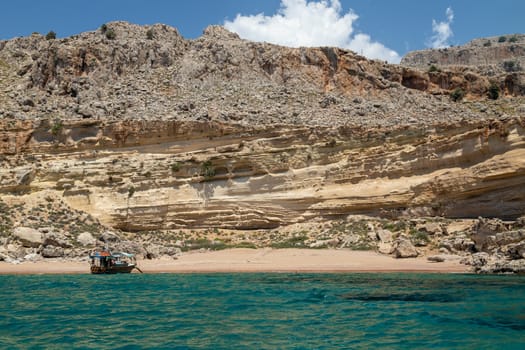 View from a motor boat on the mediterranean sea at the rocky coastline near Stegna on the eastside of Greek island Rhodes on a sunny day in spring