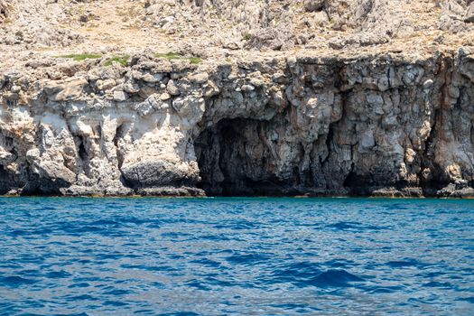 View from a motor boat on the mediterranean sea at the rocky coastline near Stegna on the eastside of Greek island Rhodes on a sunny day in spring