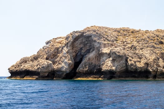 View from a motor boat on the mediterranean sea at the rocky coastline near Lindos on the eastside of Greek island Rhodes on a sunny day in spring