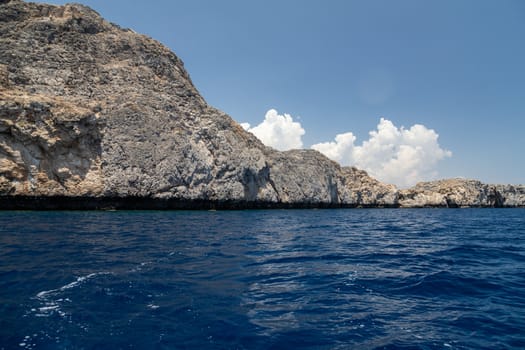 View from a motor boat on the mediterranean sea at the rocky coastline near Lindos on the eastside of Greek island Rhodes on a sunny day in spring