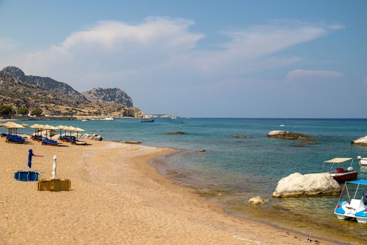 Stegna beach on Greek island Rhodes with sand, sunshades and boats in the background on a sunny day in spring