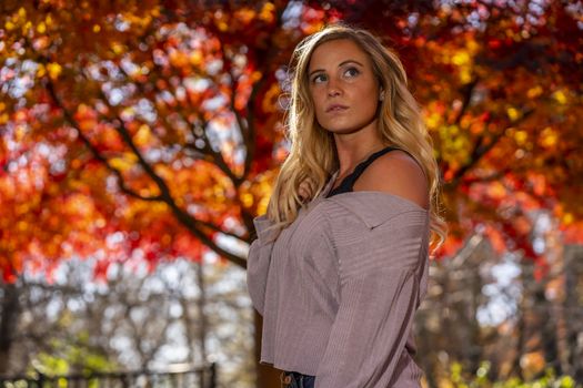 A gorgeous blonde model enjoys a Autumn day outdoors in a park