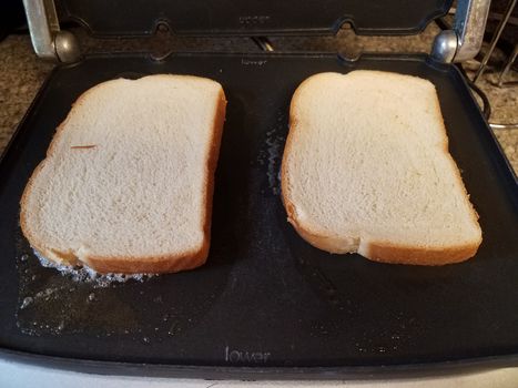 slices of white bread and butter cooking on grill