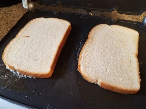 slices of white bread and butter cooking on grill