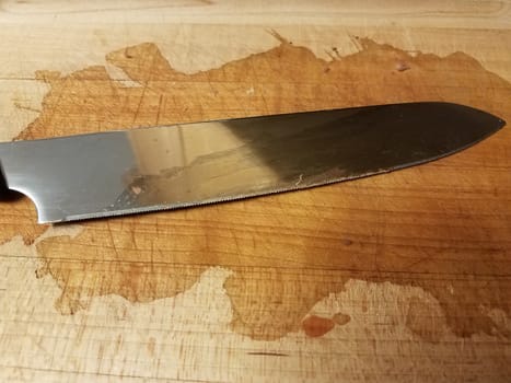 sharp metal knife on wood cutting board with stain