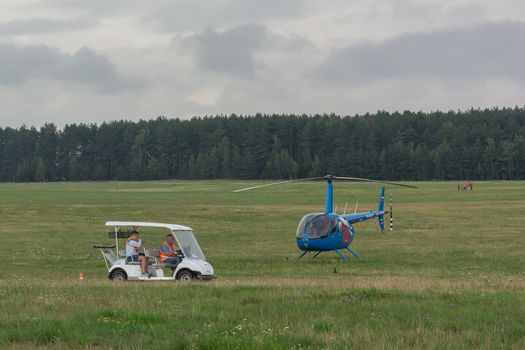 Belarus, Minsk - 07/25/2018: electric car and two-seater helicopter on the green field of the airfield. Stock photography