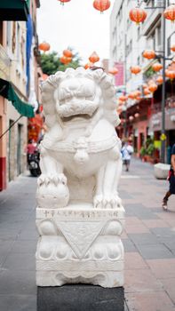 Portrait style picture of a chinese stone statue of a dragon in the chinatown alley