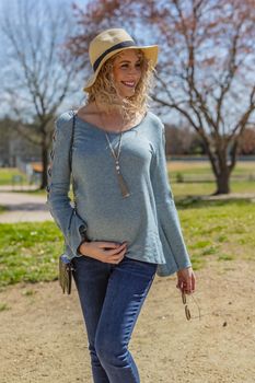 A pregnant blonde model poses for images in an outdoor environment