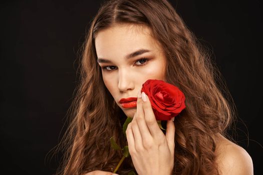 woman with a red rose on a dark background long hair makeup red lips. High quality photo