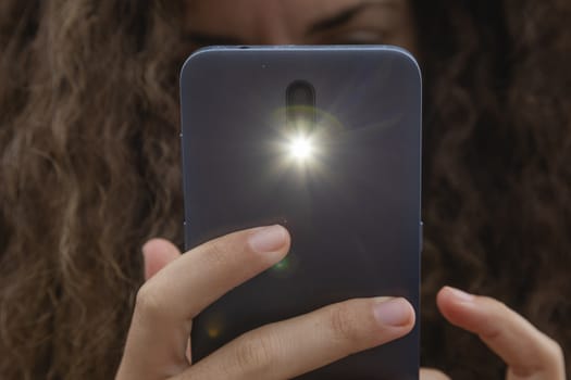 A young woman takes a photograph with a smart mobile phone, Spain.