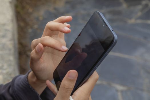 A young woman, holds with her right hand a smart mobile phone, Spain.