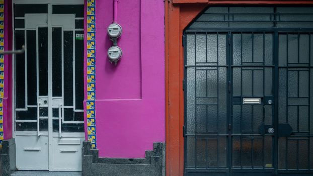 Picture of the front side of a pink house and an orange house next to each other