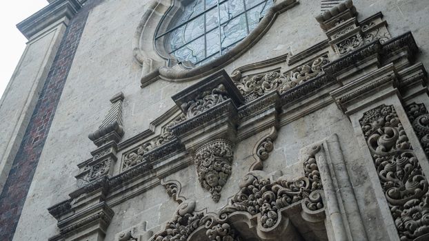 Low angle picture of a sculpted arch under a window from a building with byzantine architecture