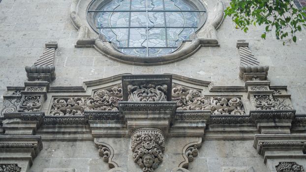 Low angle picture of a sculpted arch under a window from a building with byzantine architecture