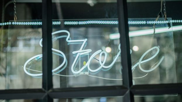 Picture of a blue Store light sign on a window from barber shop and tattoo studio