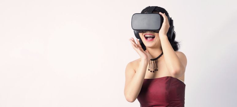 Asian teen woman wearing VR or Virtual Reality head set for enter to the digital simulation world for learning and traveling or gaming  and more. Studio shot white background