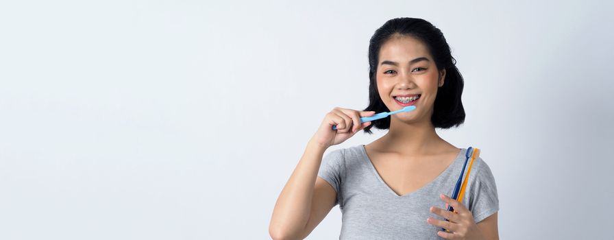 Asian teen facial with braces and smiling to camera to show dental orthodonic teeth which include professional metal wire material from orthodontist. studio shot white background.