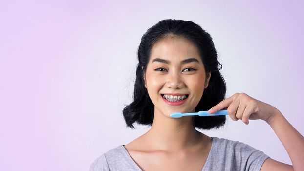 Asian teen facial with braces and smiling to camera to show dental orthodonic teeth which include professional metal wire material from orthodontist. studio shot white background.