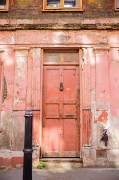 Portrait View of a Deteriorated Red Door on a building with a little girl painted on a wall