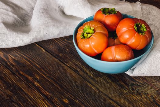 Persimmons in Blue Bowl with White Cloth on Table