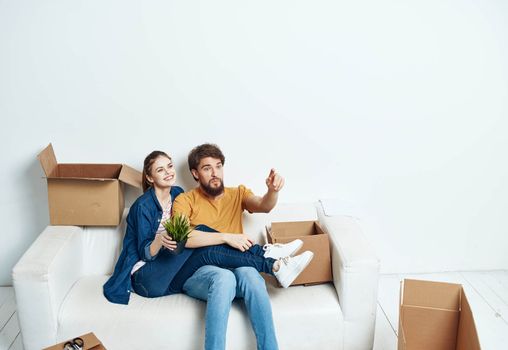 young couple sitting on white couch boxes moving lifestyle. High quality photo