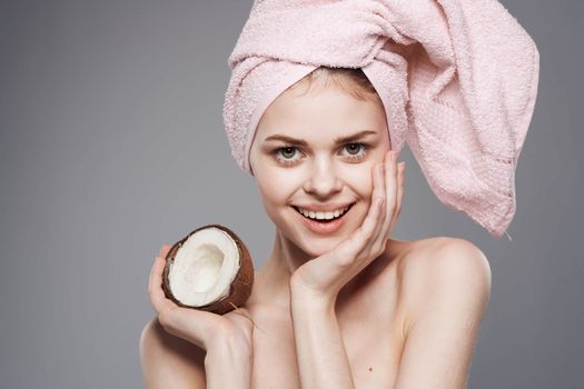 Cheerful woman with pink towel on her head coconut spa treatments clean skin health. High quality photo