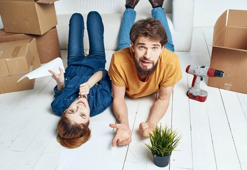 To women men on a wooden floor with boxes and a flower in a pot. High quality photo