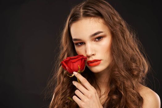 woman with a red rose on a dark background long hair makeup red lips. High quality photo