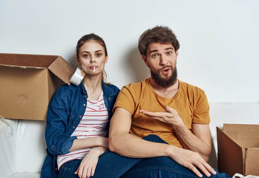 Emotional young couple on the couch with cardboard boxes interior. High quality photo