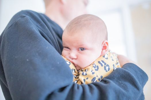 Picture of a Bored Baby Girl looking at the camera while wearing a cheetah pattern onesie in the Arms of Her Granddad