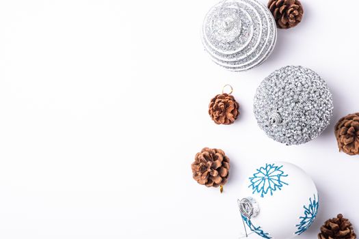 Christmas New Year composition. Gifts, fir tree cones, silver ball decorations on white background. Winter holidays concept. Top view copy space