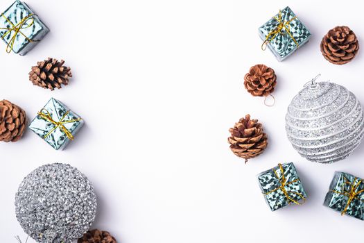 Christmas New Year composition. Gifts, fir tree cones, silver ball decorations on white background. Winter holidays concept. Flat lay, top view, copy space