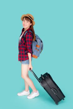 Beautiful young asian woman pulling suitcase isolated on blue background, asia girl having expressive is cheerful holding luggage in vacation, female is excited, journey and travel concept.