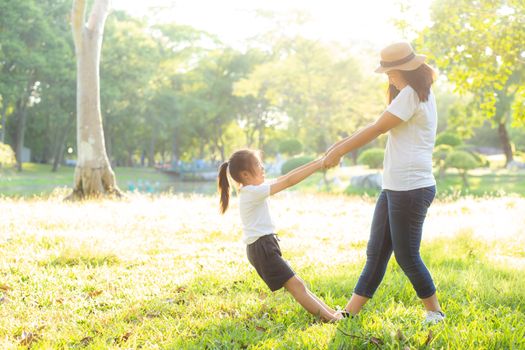 Young asian mother and little daughter playing the park with fun and happiness, family enjoy and relax and leisure together, mom and children smiling laughing in summer day.