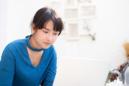 Beautiful portrait asia young woman working online on laptop sitting at cafe shop, professional female freelance using notebook computer, business and communication concept.