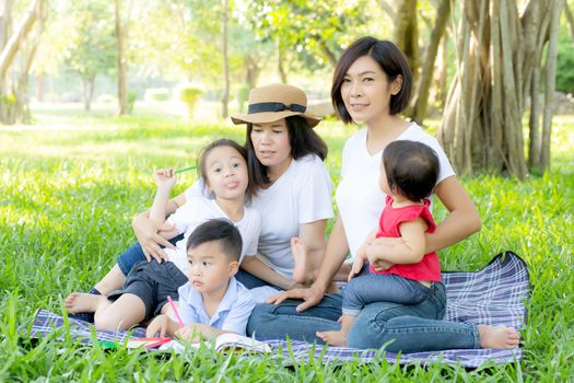 Beautiful young asian parent family portrait picnic in the park, kid or children and mother love happy and cheerful together in summer at garden, lifestyle concept.
