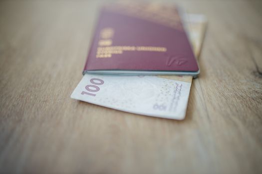 Picture of a 100 Moroccan Dirhams Bill Partially Inside a blurry Sweden Passport