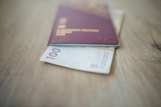 Picture of a 100 Moroccan Dirhams Bill Partially Inside a blurry Sweden Passport