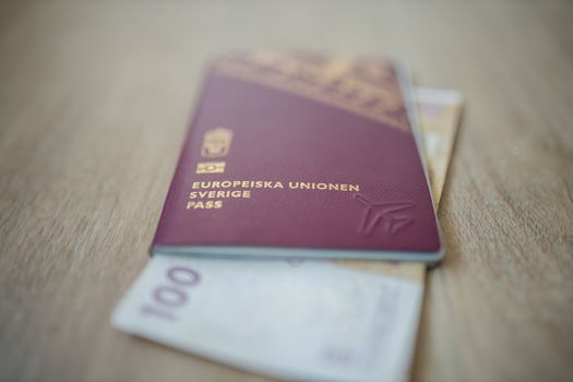 Picture of a Swidish Passport -with the words European Union Sweden Passport in Swedish- with a 100 Moroccan Dirhams Bill Partially Inside