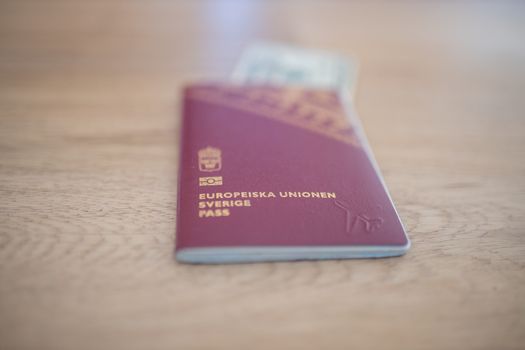 Picture of a Swedish Passport -with the words European Union Sweden Passport in Swedish- with a 20 Thai Baht Bill Partially Inside