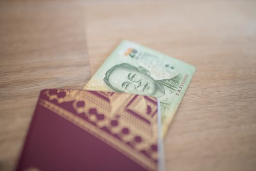 Picture of a 20 Thai Baht Bill Partially Inside a blurry Sweden Passport, showing the face of Bhumibol Adulyadej