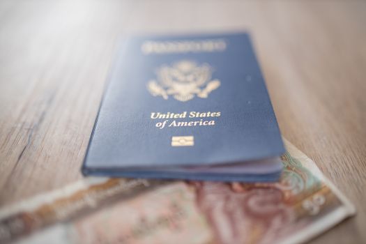 Picture of a United States of America Passport partially on top of a blurry Fifty Burmese Kyats Bill