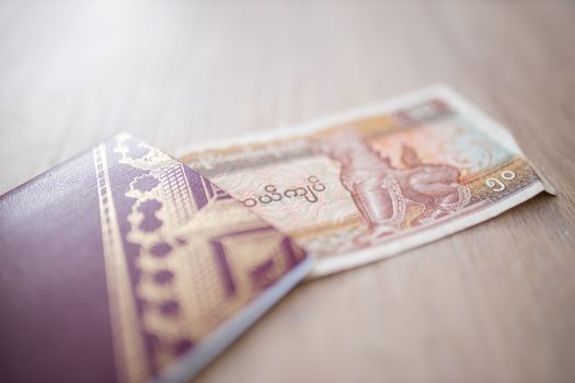 Picture of a Fifty Burmese Kyats Bill -with the words Central Bank, Fifty Kyats and the number 50 in Burmese- partially Inside a Blurry Sweden Passport